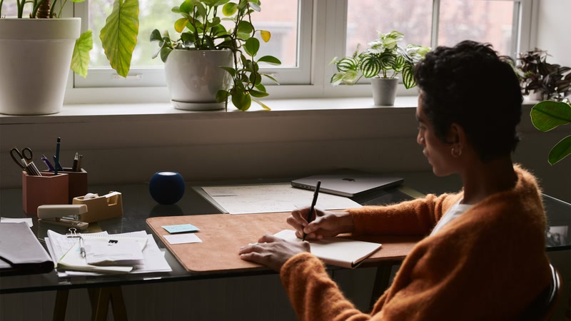 HomePod mini bleu sur un bureau près de la fenêtre