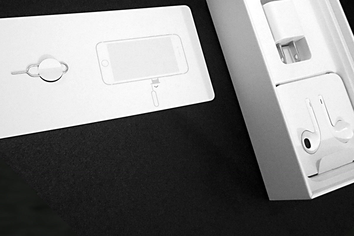 Boîte ouverte, écouteurs et outil d’éjection SIM sur leur support Apple