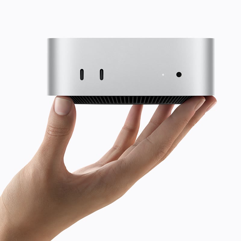Mac mini argenté dans une main, ports avant visibles